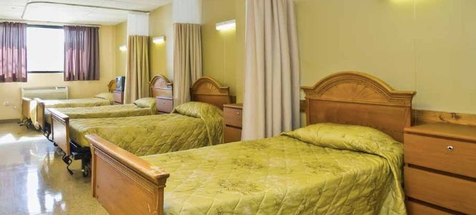 A cozy hotel room featuring two twin beds with green bedding and wooden headboards.