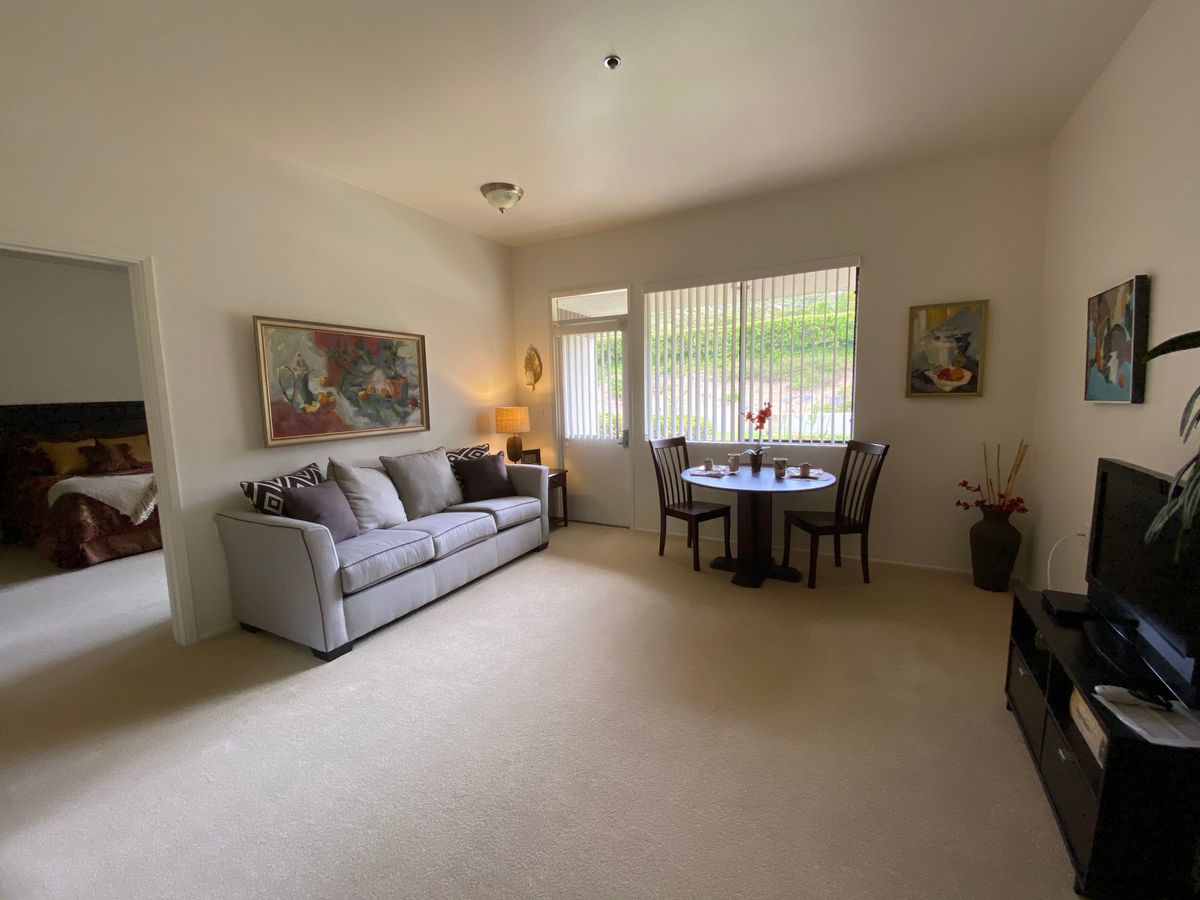 A cozy living room with a sofa, dining table, and artwork on the walls.