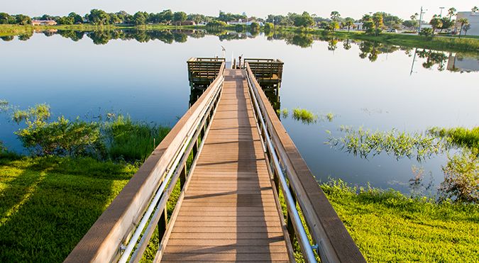 A tranquil dock extending over a serene lake with clear reflections of the surrounding landscape.
