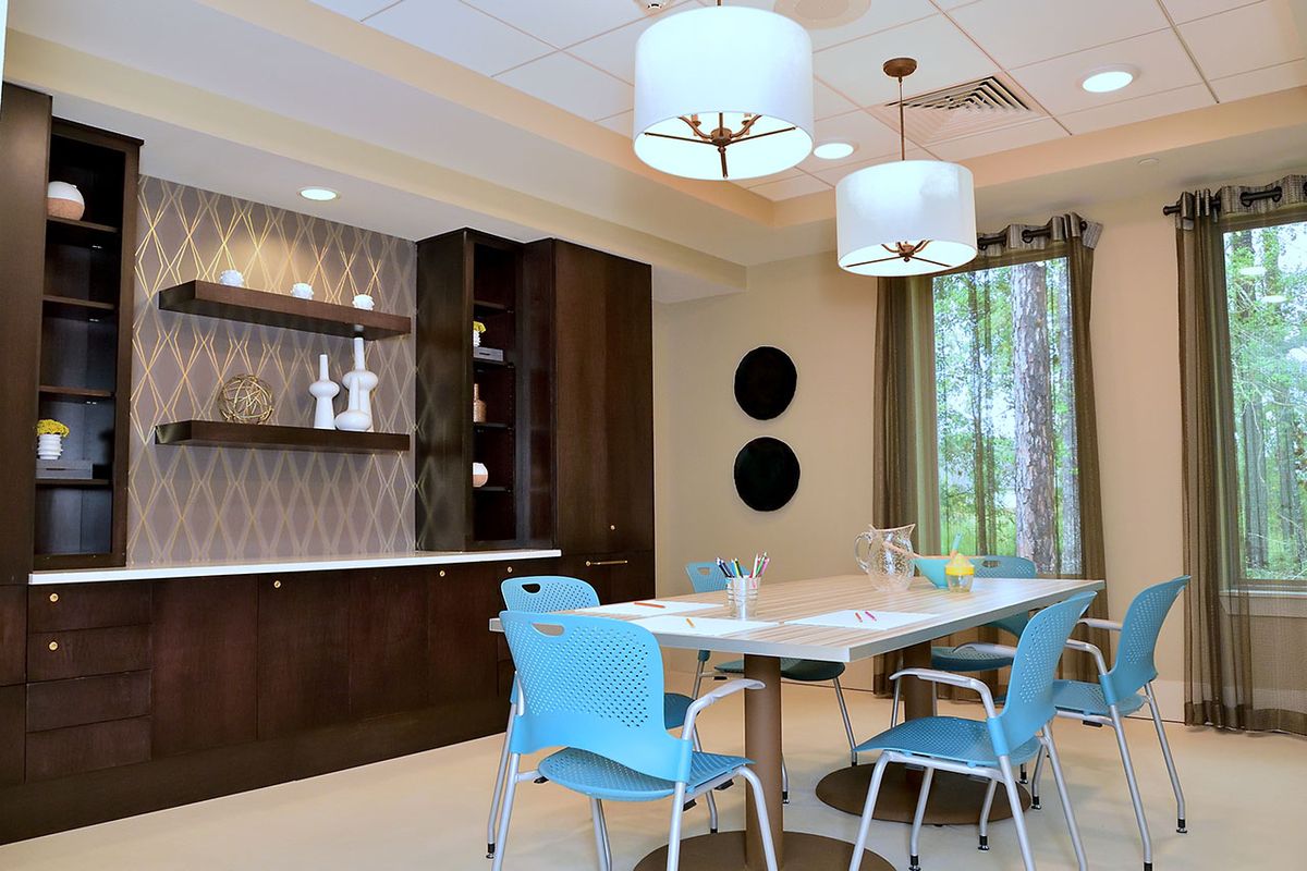 A modern dining area with blue chairs, pendant lights, and wooden cabinets.