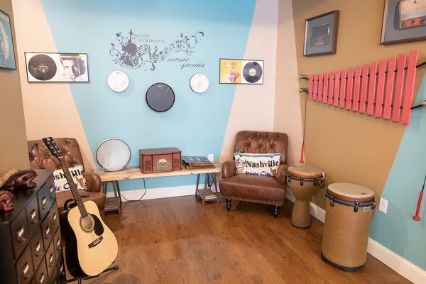 A cozy music corner featuring a guitar, various drums, and retro decorations.