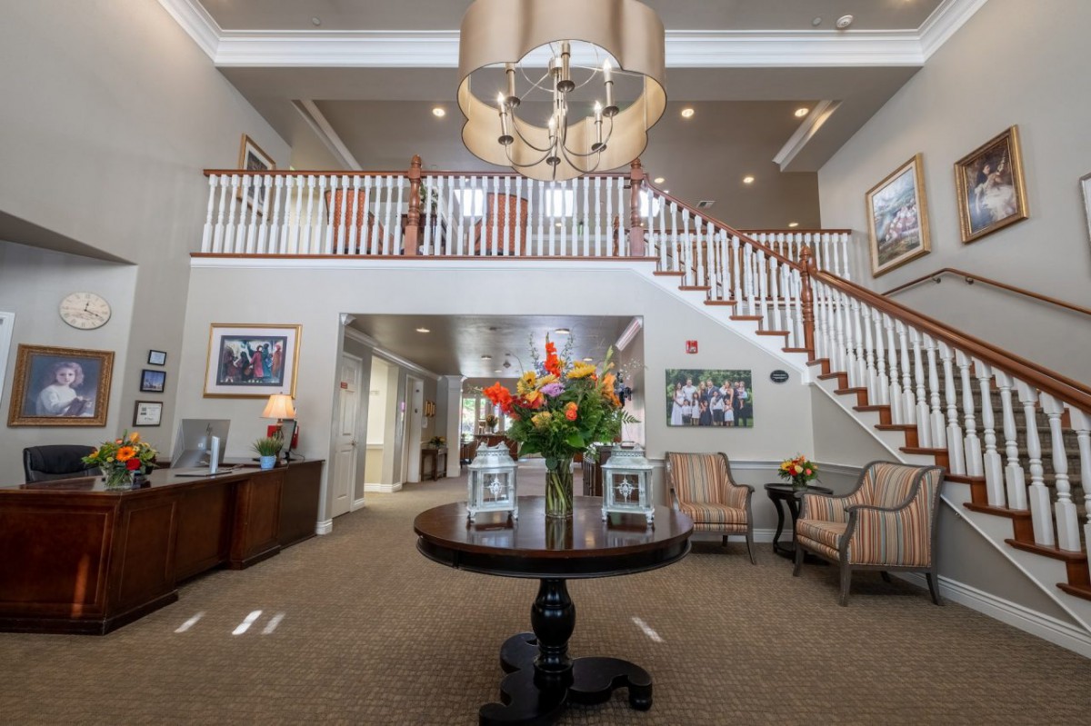 A spacious lobby with elegant decor, featuring a staircase and a central flower arrangement.