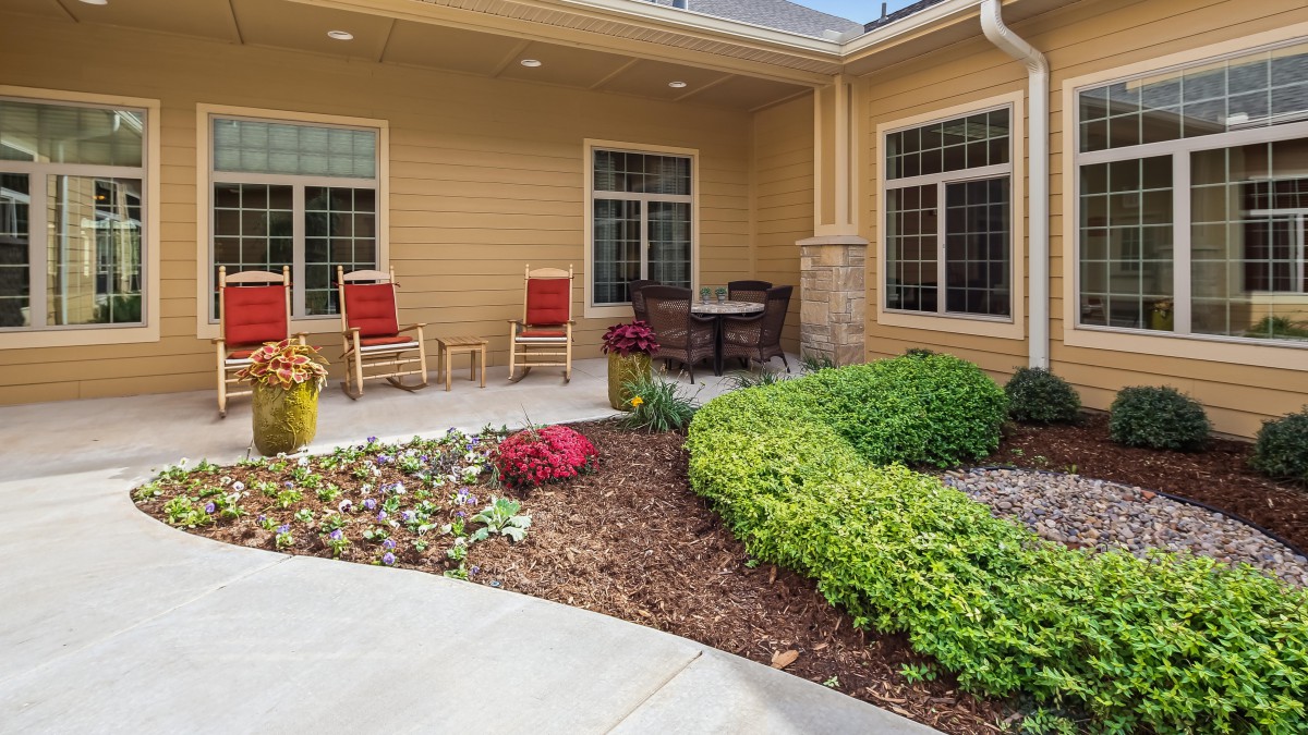 A cozy patio with rocking chairs and a neatly landscaped garden.