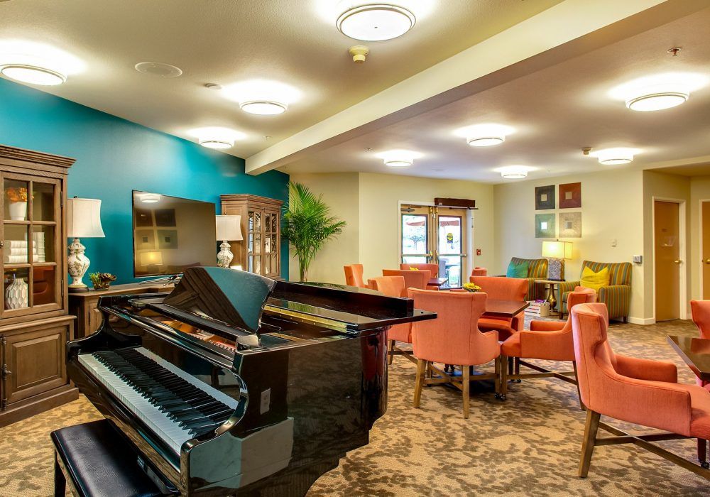 A cozy lounge with a grand piano, colorful seating, and stylish decor.
