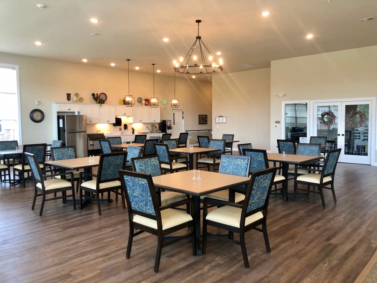 A spacious dining area with multiple tables and chairs, featuring a chandelier and modern decor.