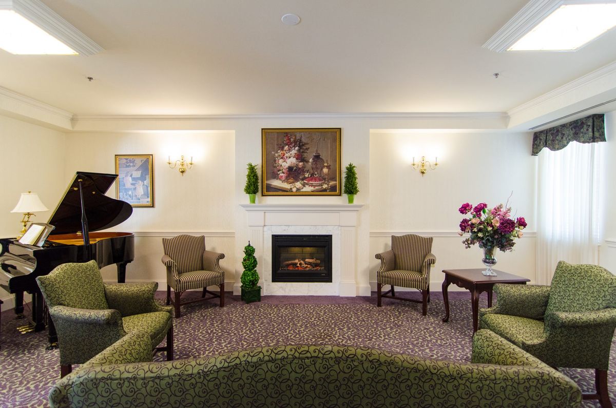 A cozy living room with a fireplace, seating area, and a grand piano.