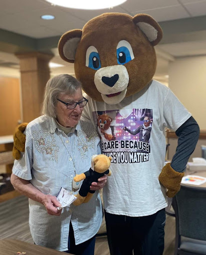 A joyful moment shared between a person and a bear mascot at an event, showcasing fun and community spirit.