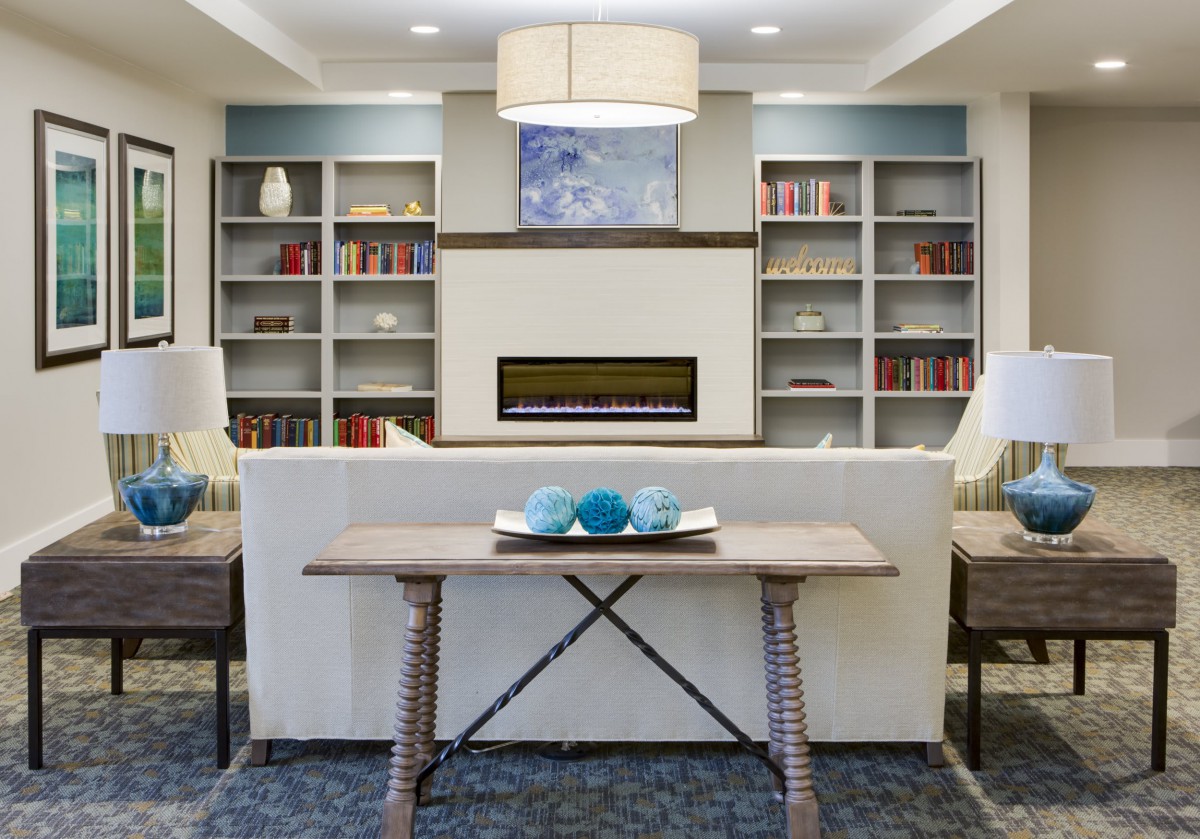 A modern living room with a cozy fireplace, surrounded by shelves filled with books and decorative items.