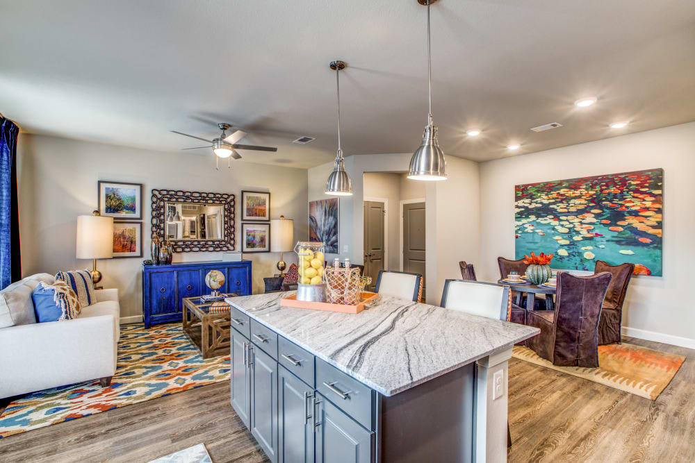 A modern open-concept living space with a stylish kitchen featuring an island countertop and pendant lighting.