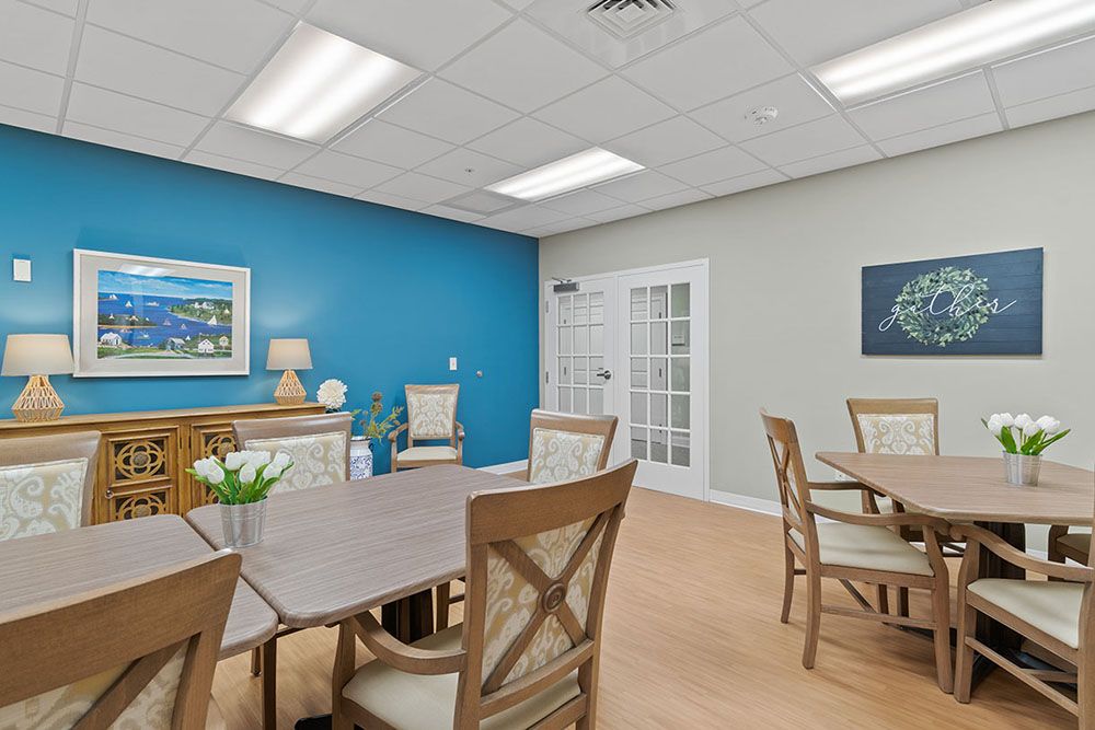 A bright and neatly organized office meeting room with a blue accent wall, featuring tables and chairs arranged for discussions.