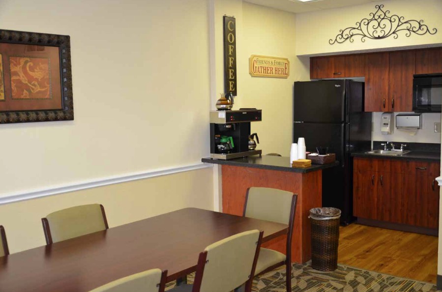 A cozy kitchen and dining area with a table, chairs, coffee machine, and refrigerator.