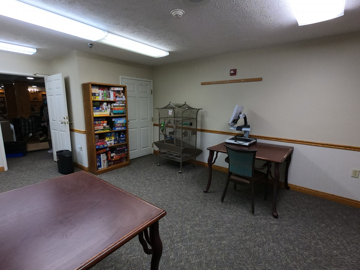 A small office space with desks, a bookshelf, and a bird cage.