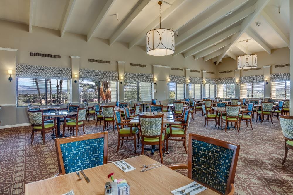 A spacious restaurant interior with neatly arranged tables and chairs, featuring large windows and stylish lighting.