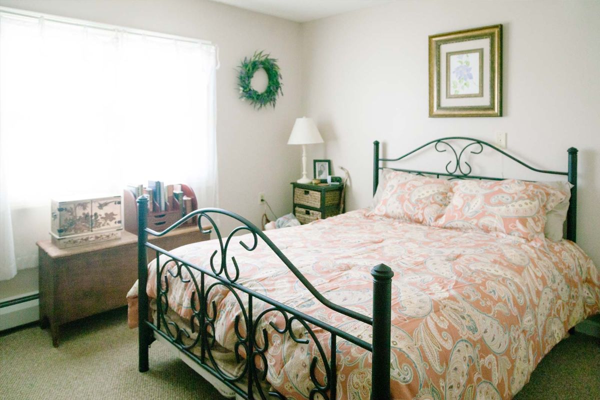A cozy bedroom with an iron bed, decorative bedding, and a warm, inviting atmosphere.