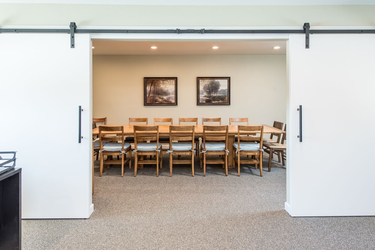A conference room with a long wooden table and multiple chairs, set up for a meeting.