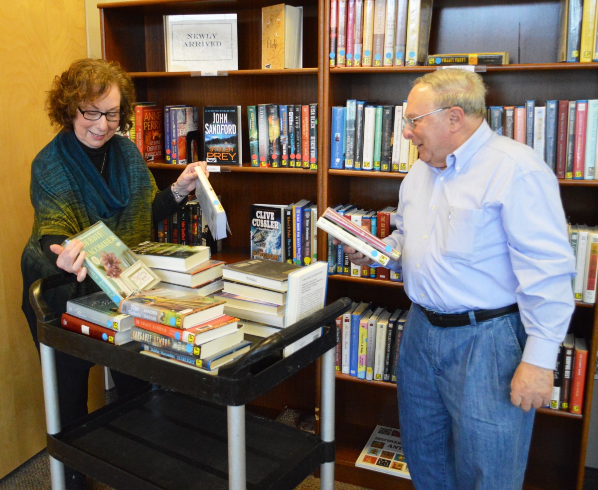 Two people organizing a collection of books in a library setting.