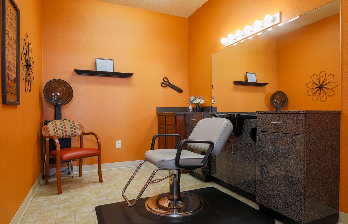 A stylish hair salon interior with vibrant orange walls and a modern setup.