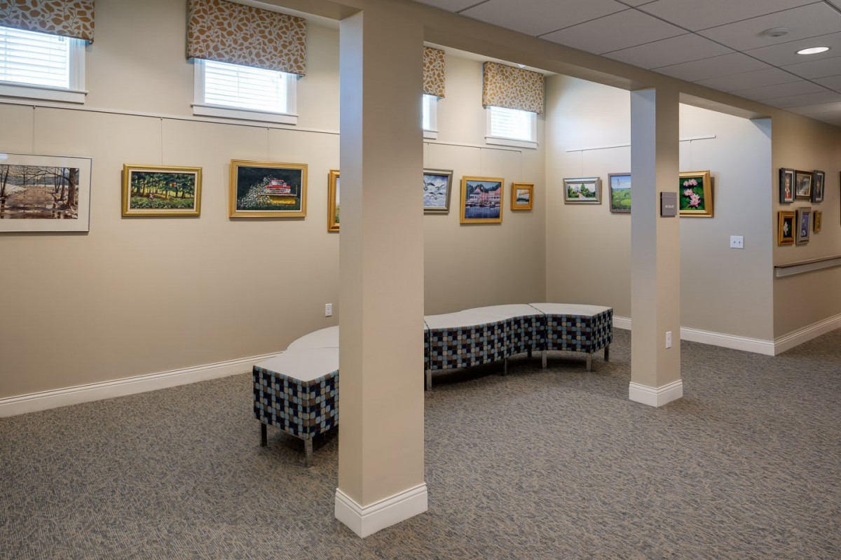 A small indoor art gallery with paintings on the walls and modern seating arrangements.