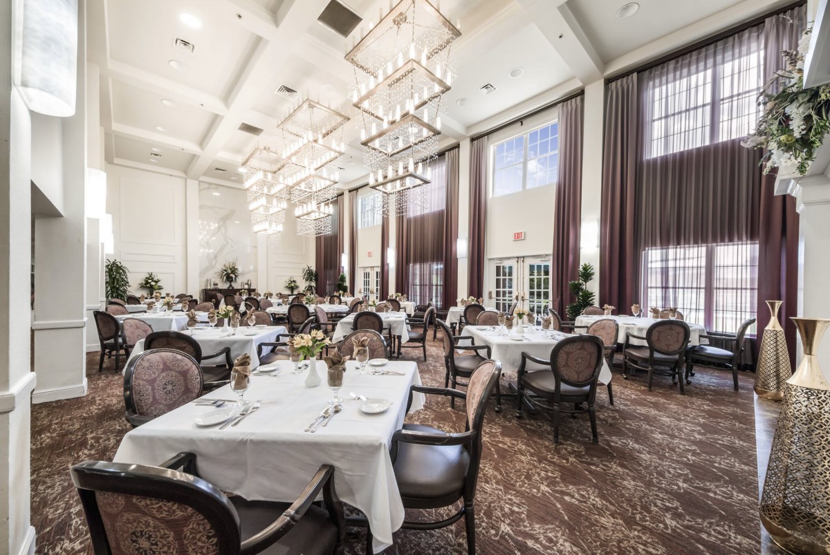 An elegant dining hall with chandeliers and tables set for guests.