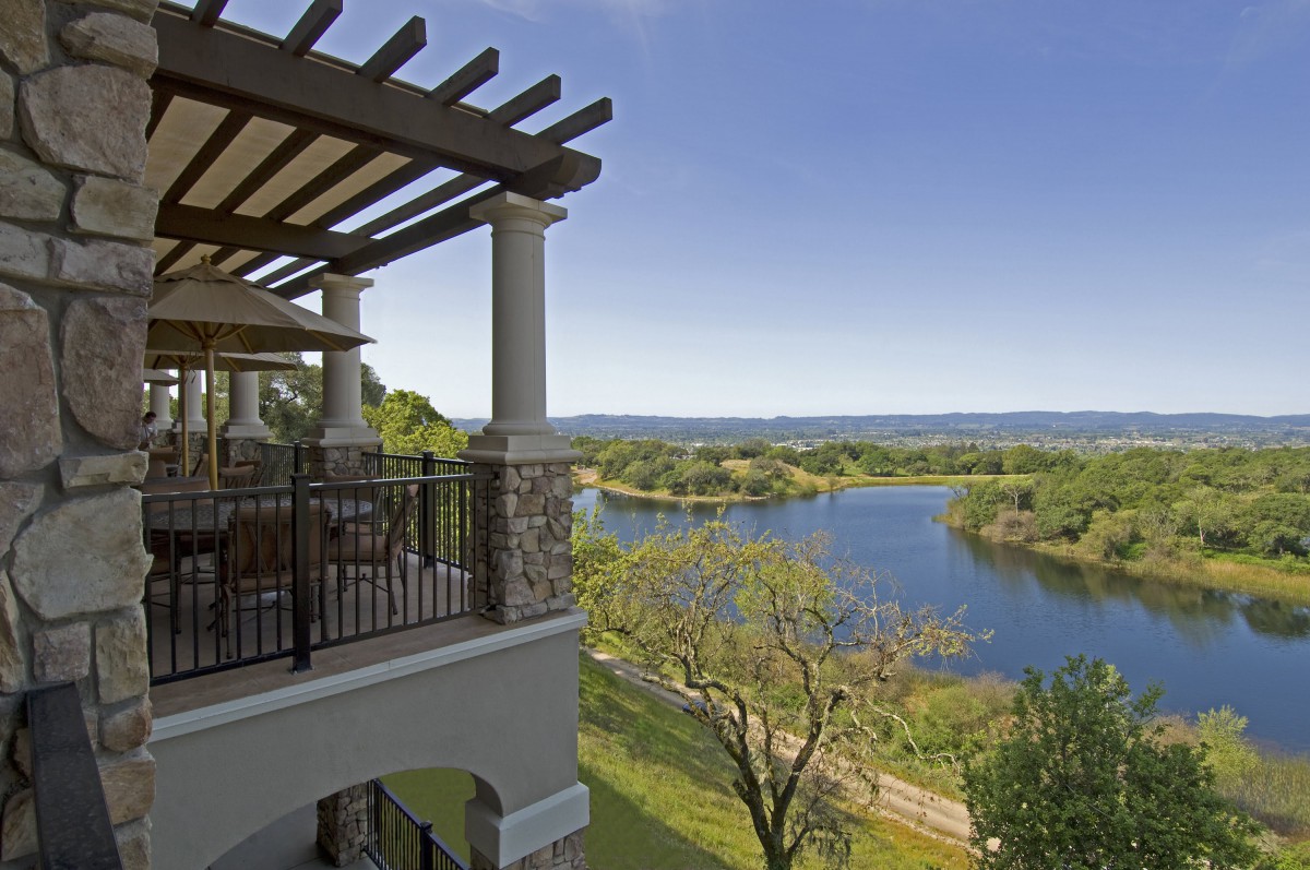 A scenic view from a balcony overlooking a beautiful lake and lush green landscape.