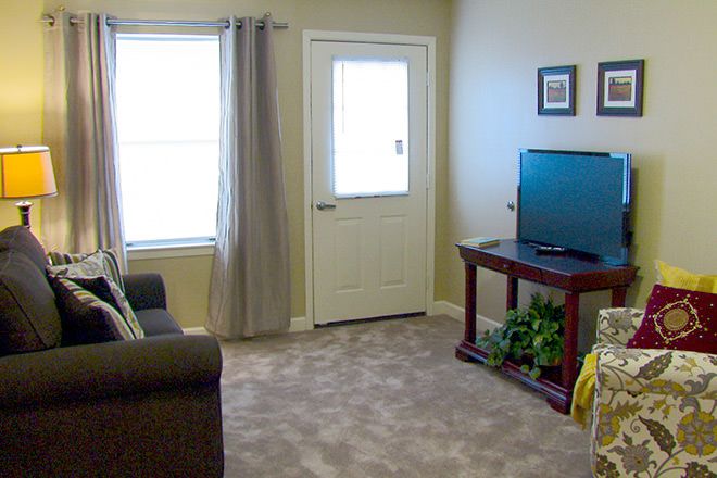 A cozy living room with a sofa, television, and a carpeted floor.