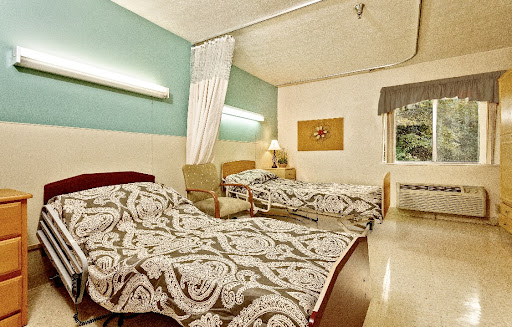 A cozy hospital room featuring two neatly made beds and soft lighting.
