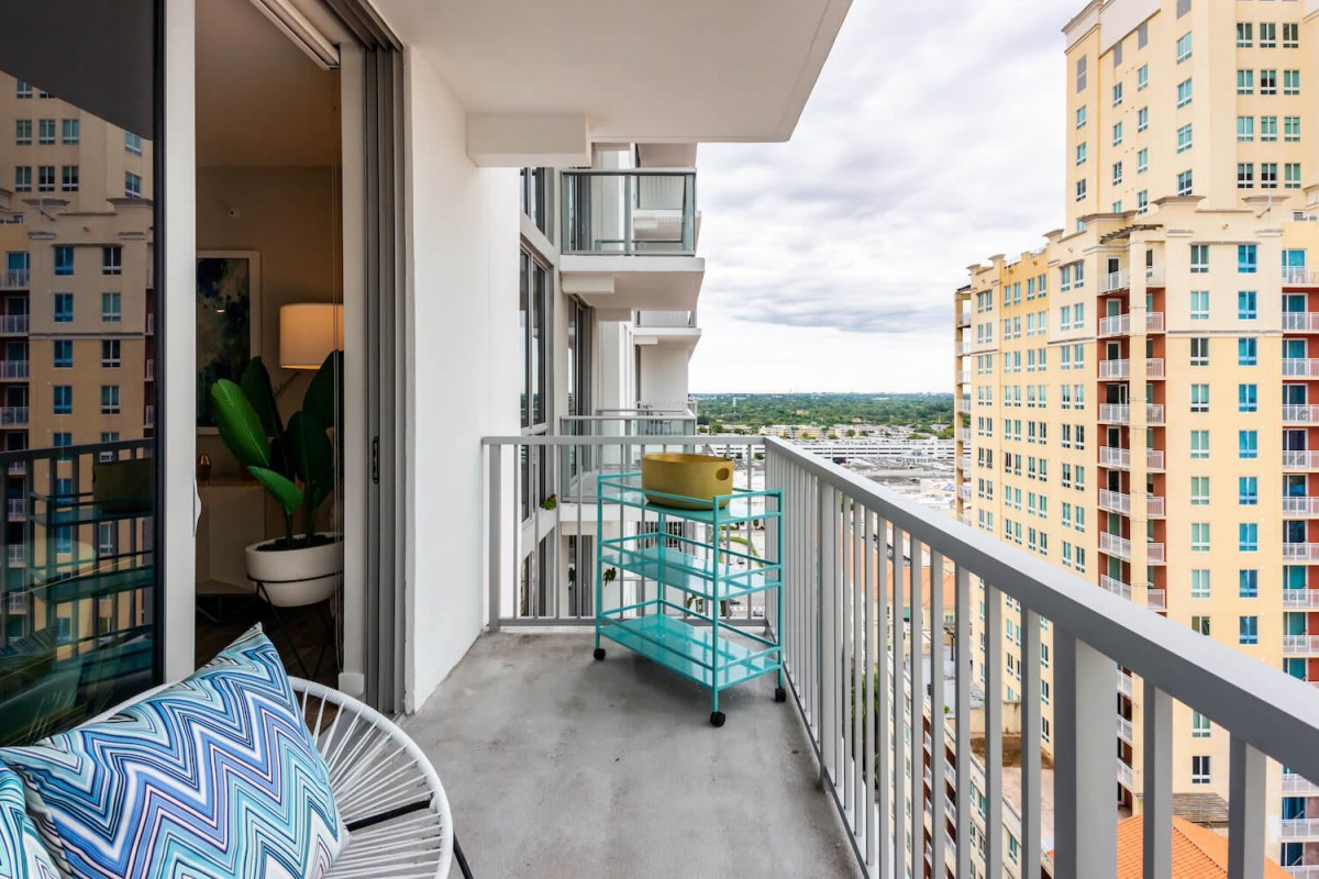 A modern apartment balcony with a city view, featuring outdoor furniture and decor.
