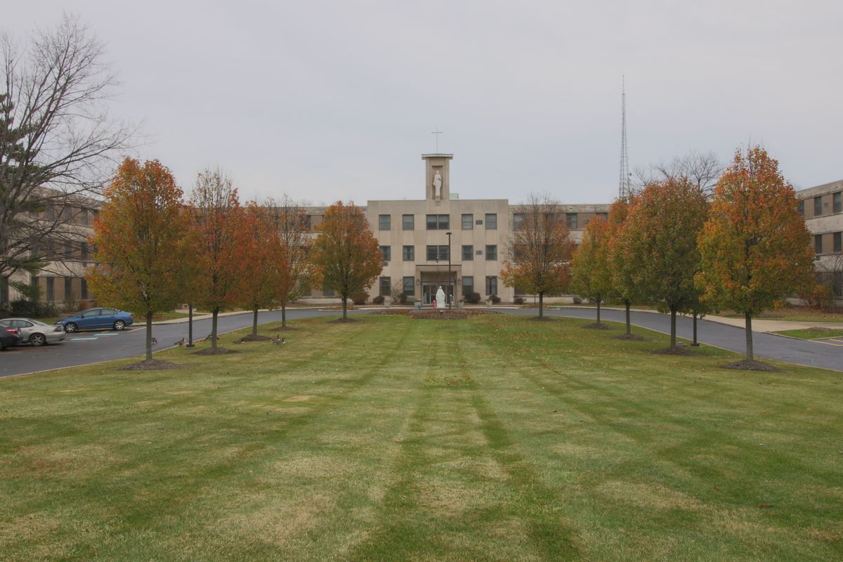 A symmetrical view of a building surrounded by autumn trees and a well-maintained lawn.