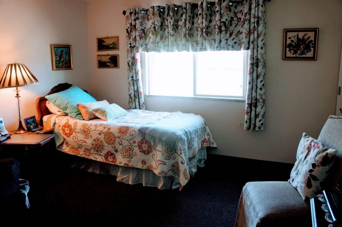A cozy bedroom with two single beds, floral bedding, and a window with patterned curtains.