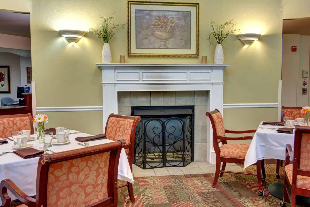 A cozy dining area featuring an elegant fireplace and well-set tables.