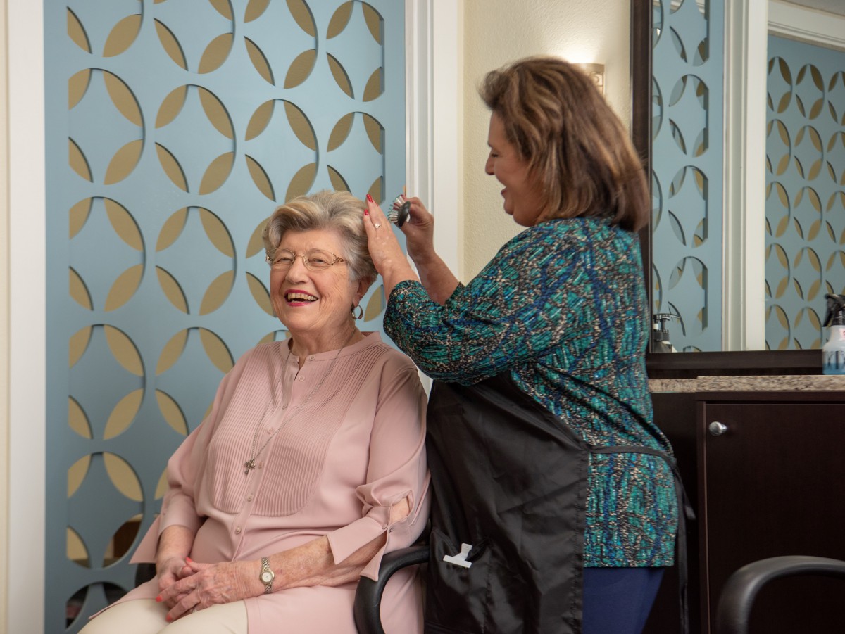 An elderly woman is getting her hair styled by a hairdresser in a salon.