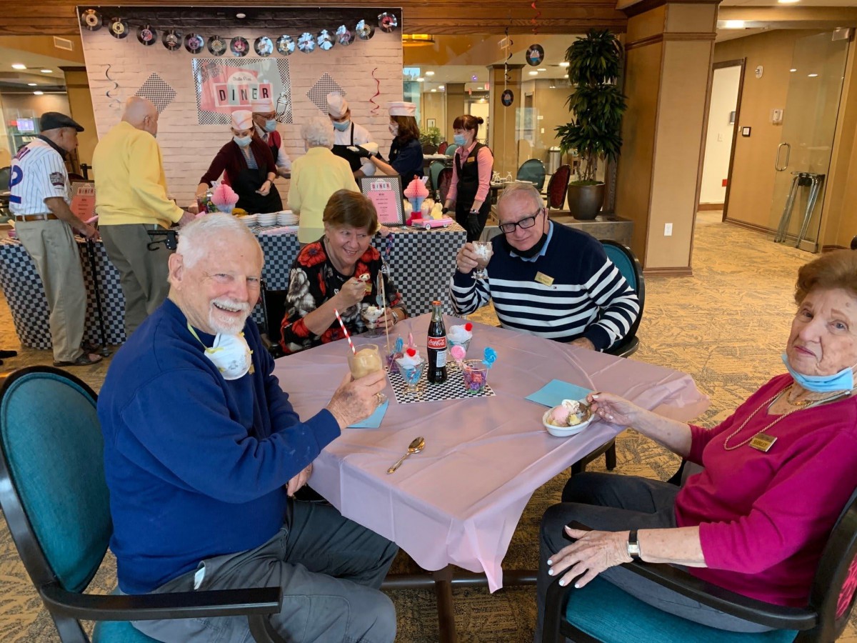 A group of elderly people enjoying ice cream at a social gathering indoors.