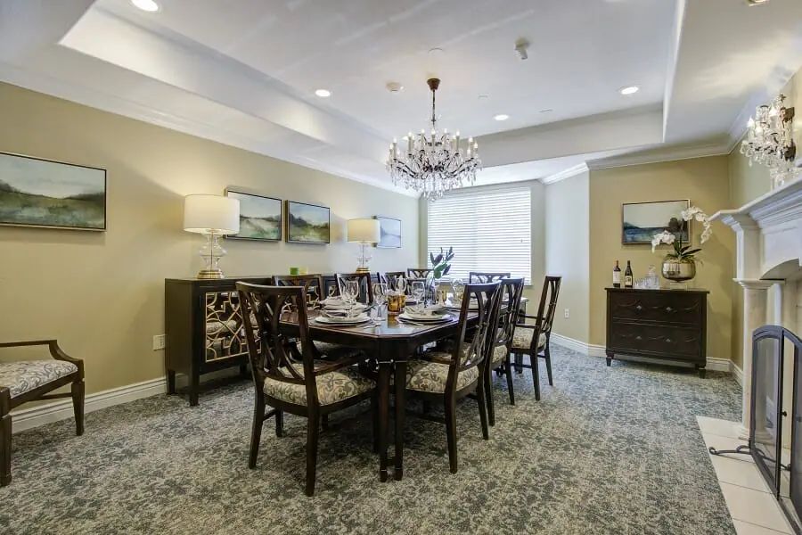 A well-decorated dining room featuring a large table with chairs, elegant chandelier, and framed artwork on the walls.