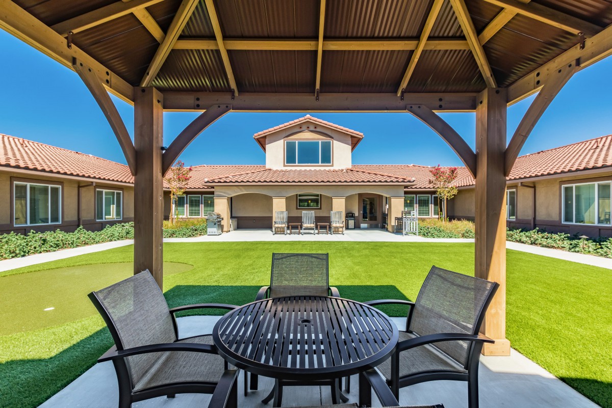 View of a house from a gazebo with patio furniture and a well-maintained lawn.
