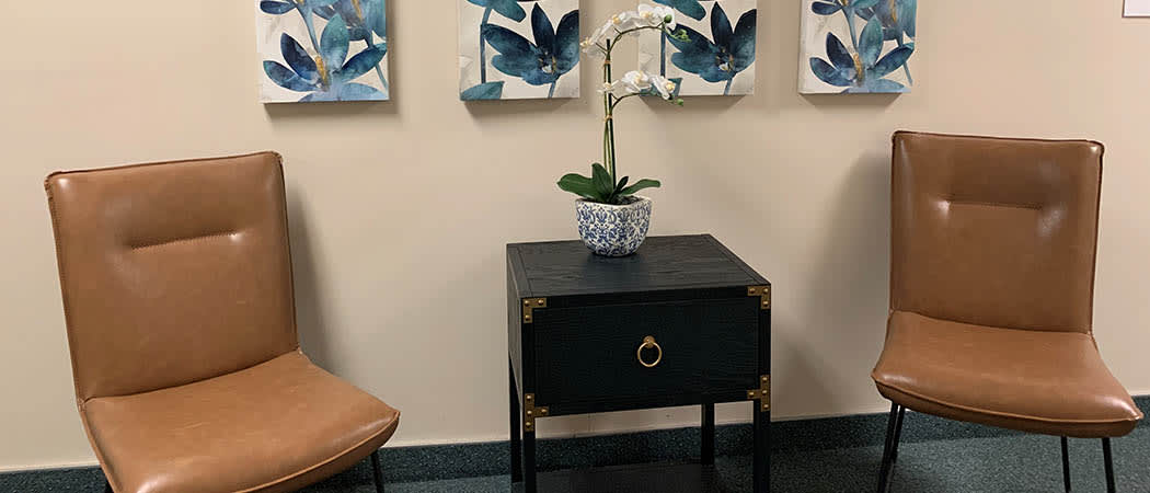 A small black table with a potted orchid, accompanied by abstract blue artwork on the wall.