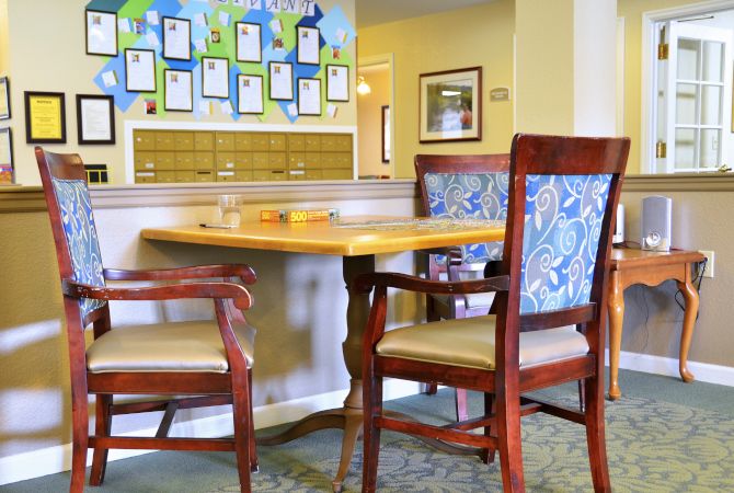 A cozy seating area in a lobby with a wooden table and upholstered chairs.
