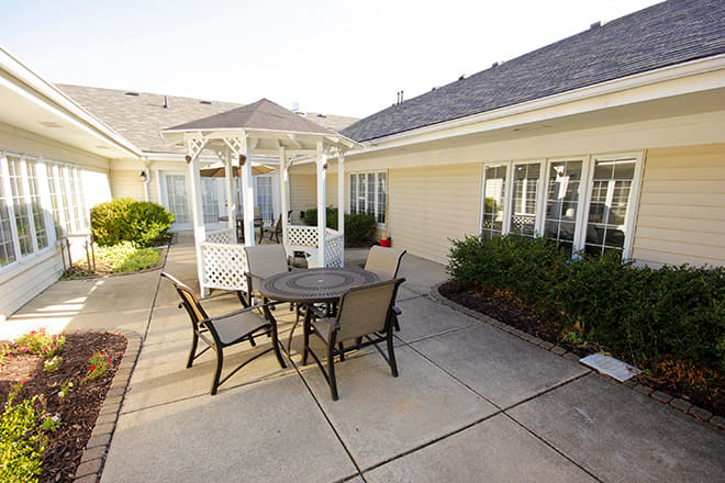 A sunny outdoor patio featuring a table and chairs next to a white gazebo.