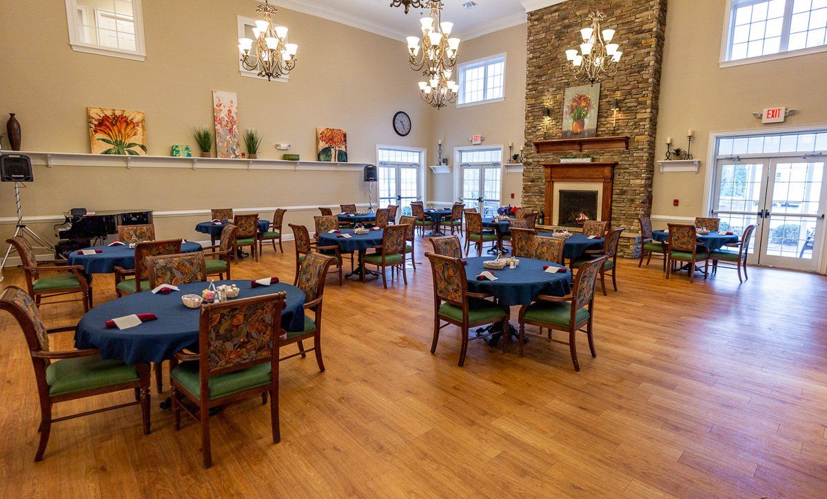An elegant dining room with multiple round tables, chandeliers, and a fireplace.