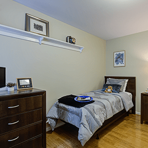 A neatly arranged minimalist bedroom with a single bed, dresser, and subtle decor.