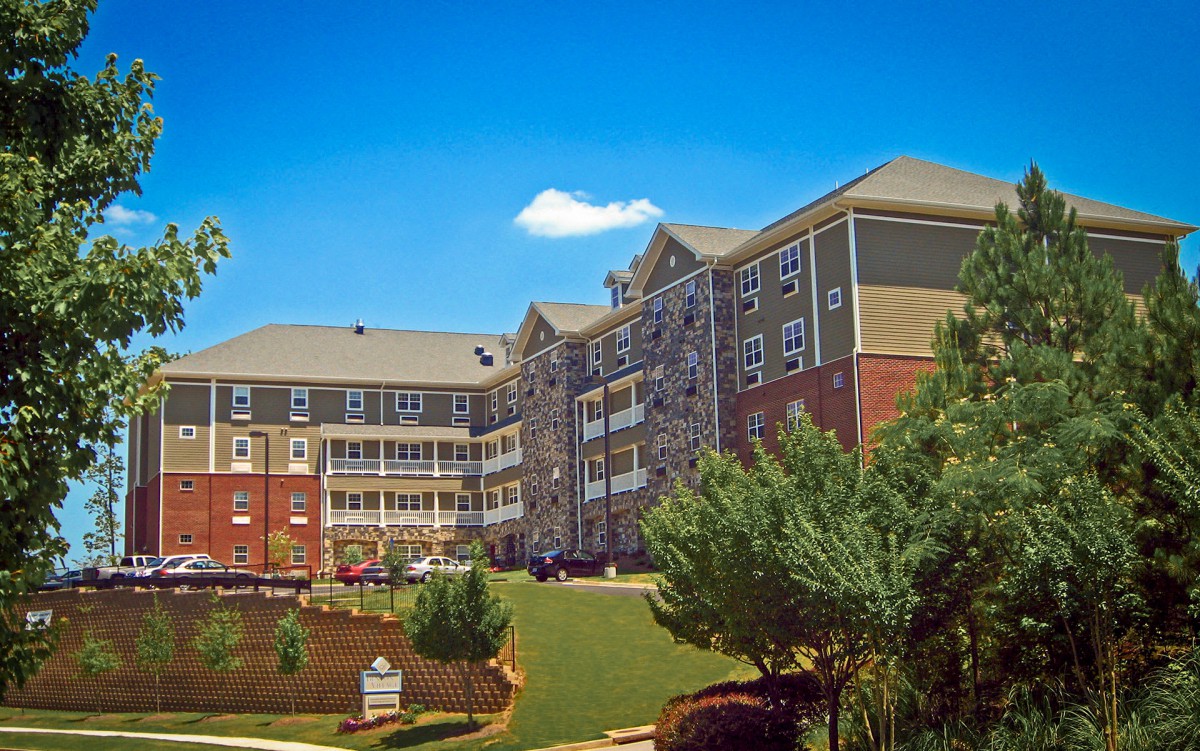 A residential apartment building with a landscaped garden and clear blue sky.