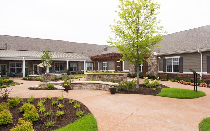 A beautifully landscaped courtyard with pathways and lush greenery in front of a modern building.