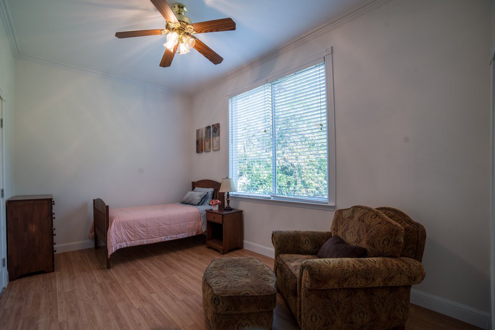 A cozy bedroom with a single bed, armchair, and large window allowing natural light.