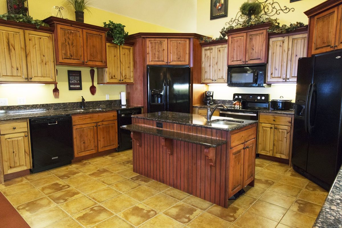 A spacious kitchen featuring wooden cabinets, a central island, and modern appliances.