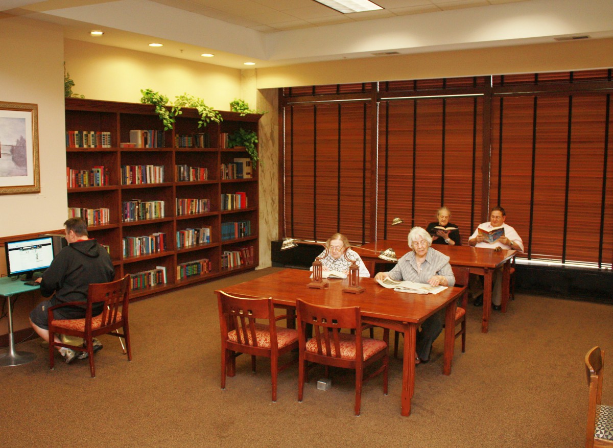 A cozy library reading room with people studying at tables.