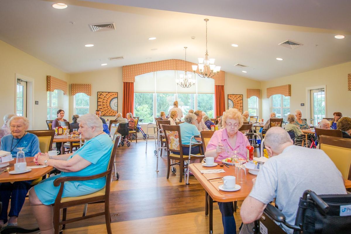 A group of seniors enjoying a meal together in a well-lit dining area.