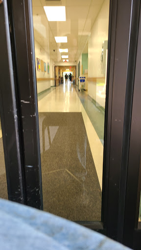A view of a hallway through open doors, showcasing the smooth floor and distant figures.