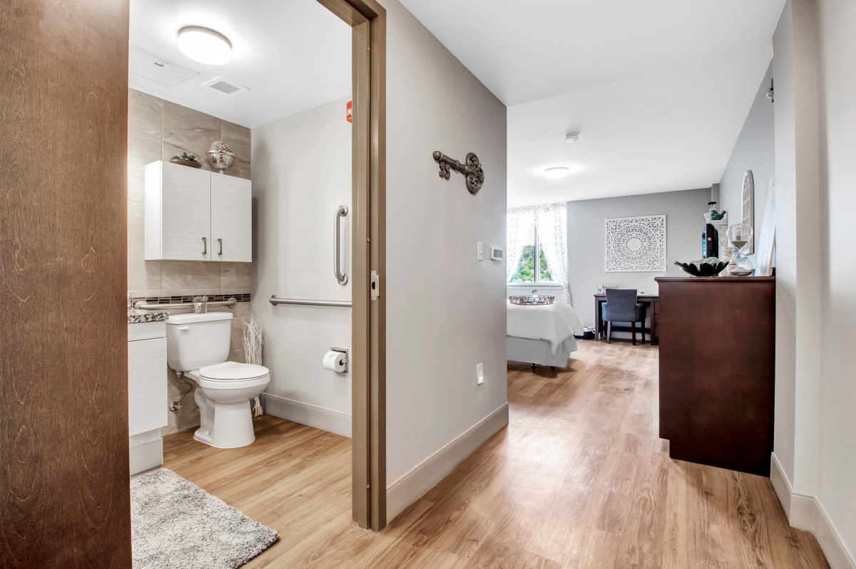 A modern and stylish interior featuring a bathroom and adjacent bedroom area with hardwood flooring.