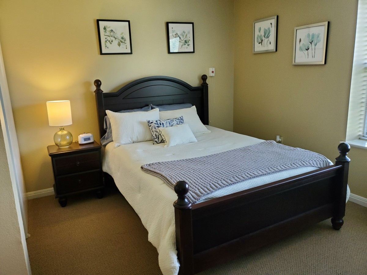 A neatly organized bedroom with a double bed, nightstand, and decorative wall art.