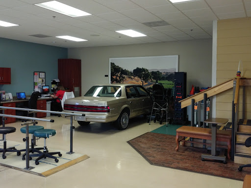A physical therapy room featuring a car as part of the rehabilitation equipment.