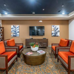 A modern living room with orange seating, a coffee table, and wall-mounted TV.
